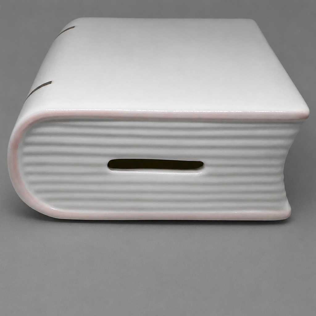 Coin slot on top of white porcelain baby bank.