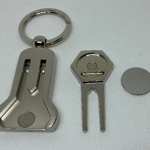 Metal keychain, divot tool, and coin on a light gray background