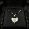 Silver heart-shaped locket on a chain in a black jewelry box