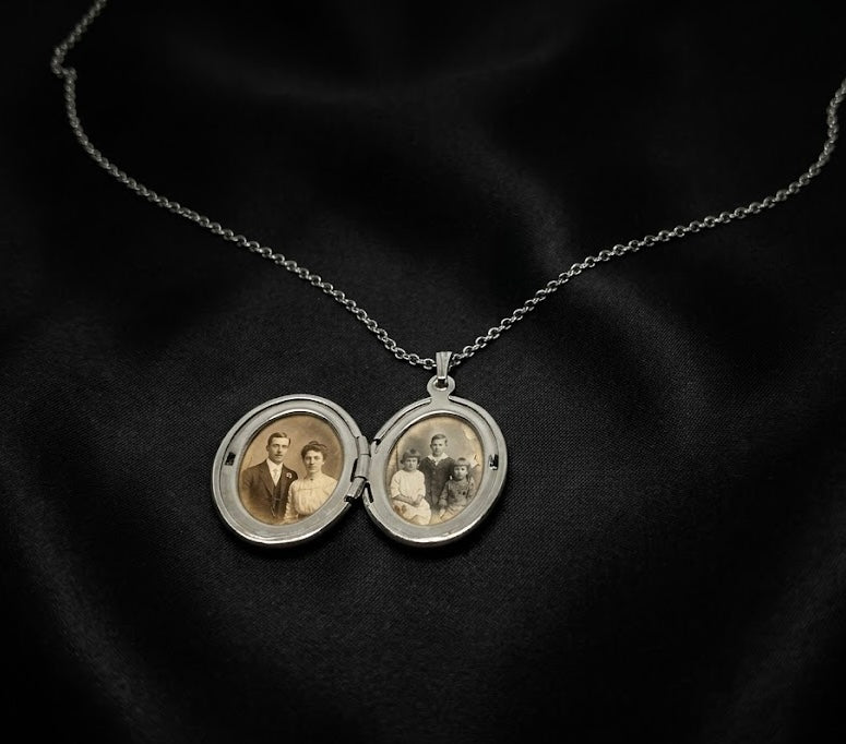 Vintage silver locket with family portraits on a dark fabric background