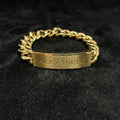 Gold chain bracelet with 'ALEXANDER' engraving on a black textured background