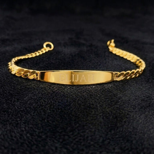 Gold bracelet with engraved name on a black textured background