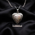 Silver heart-shaped locket with 'Mom' engraving on a black fabric background