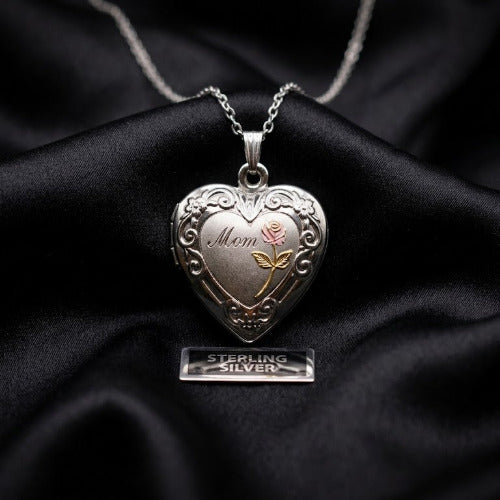 Silver heart-shaped locket with 'Mom' engraving on a black fabric background