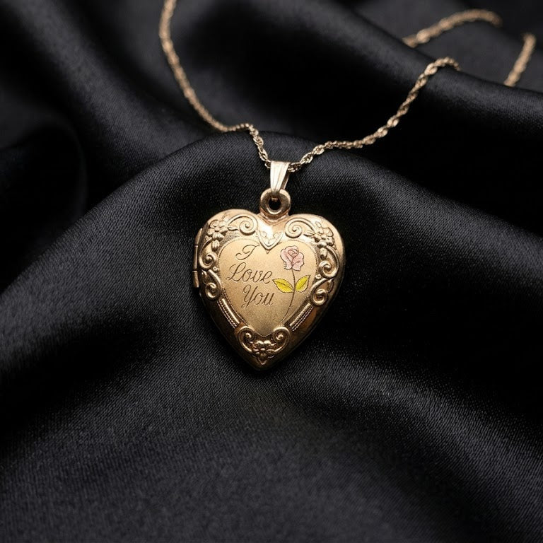 Heart-shaped gold locket with 'I love you' engraving on a black fabric background