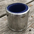 Metallic container with blue interior on a wooden surface