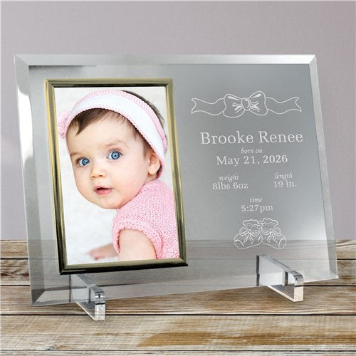 Glass photo frame with engraved baby details and a photo of a baby wearing a pink hat.