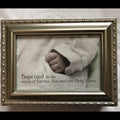 Framed photo of a baby's hand with religious text on a soft background on the cover of a music box.