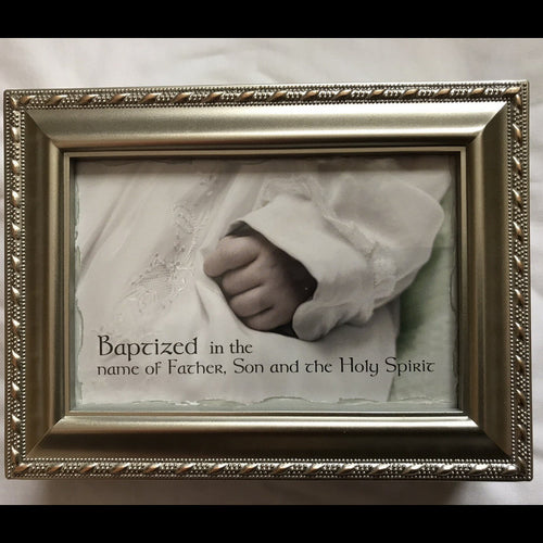 Framed photo of a baby's hand with religious text on a soft background on the cover of a music box.