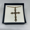 Bronze cross necklace in a black box on a white background