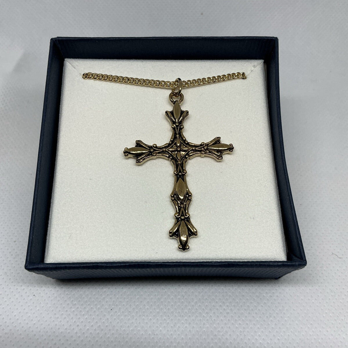 Bronze cross necklace in a black box on a white background