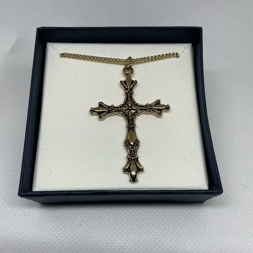 Bronze cross necklace in a black box on a white background