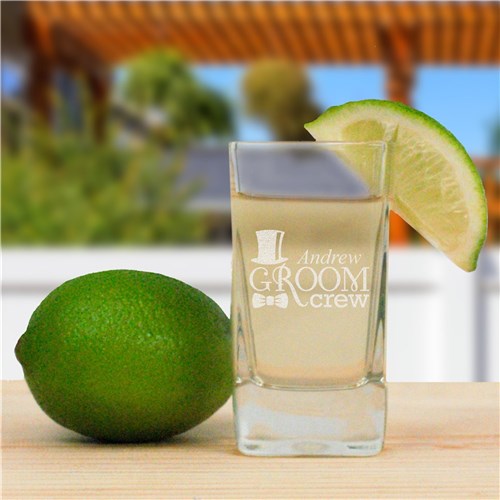 Shot glass with 'Groom' engraving next to a lime on a wooden surface