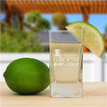 Shot glass with 'Groom' engraving next to a lime on a wooden surface